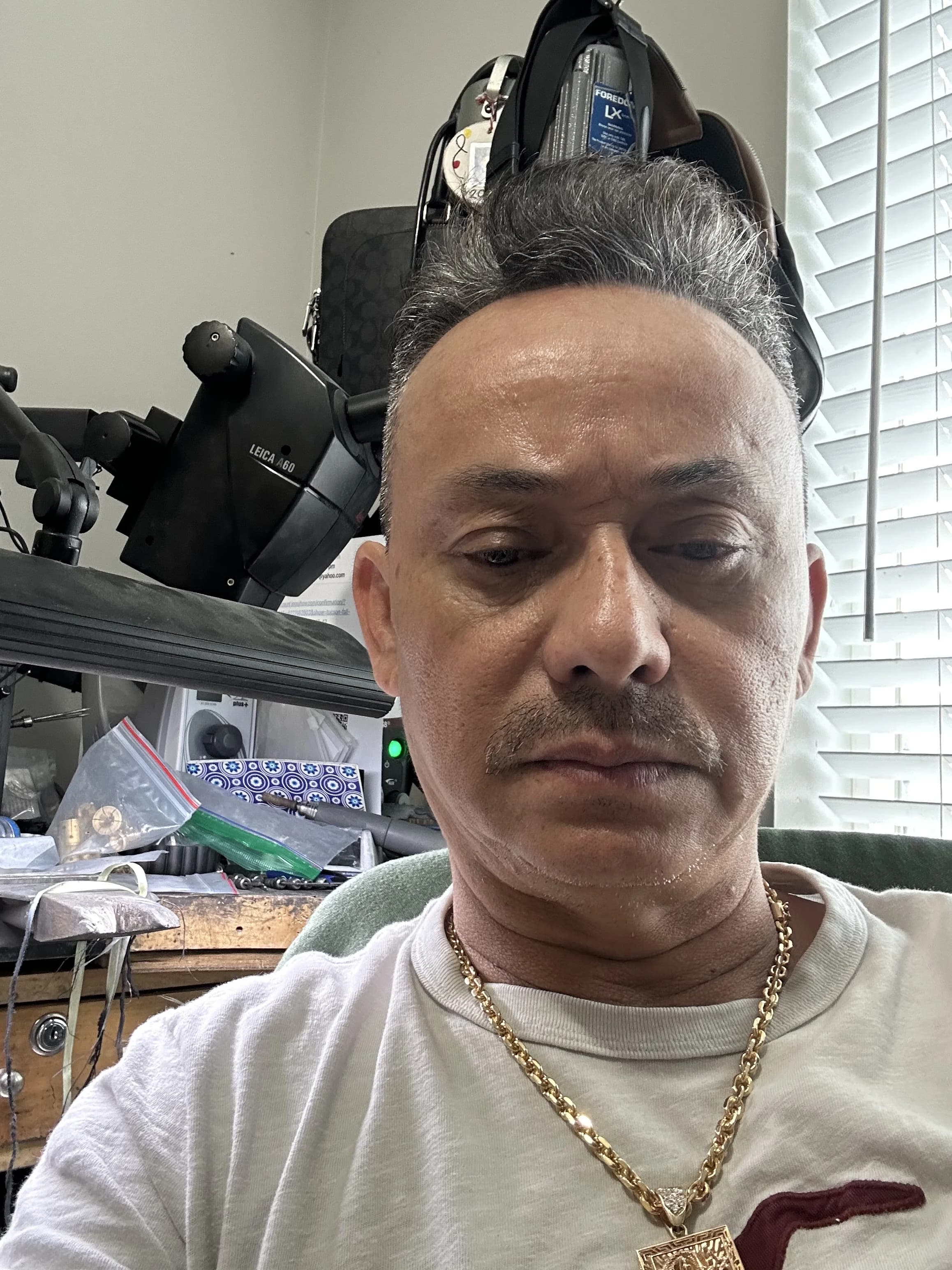 Dat Le at his jeweler's bench, with a bench microscope and hand tools behind him