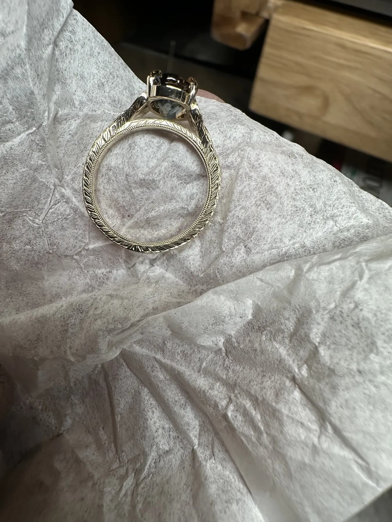 Side view of an ornate yellow-toned ring with engraved band details