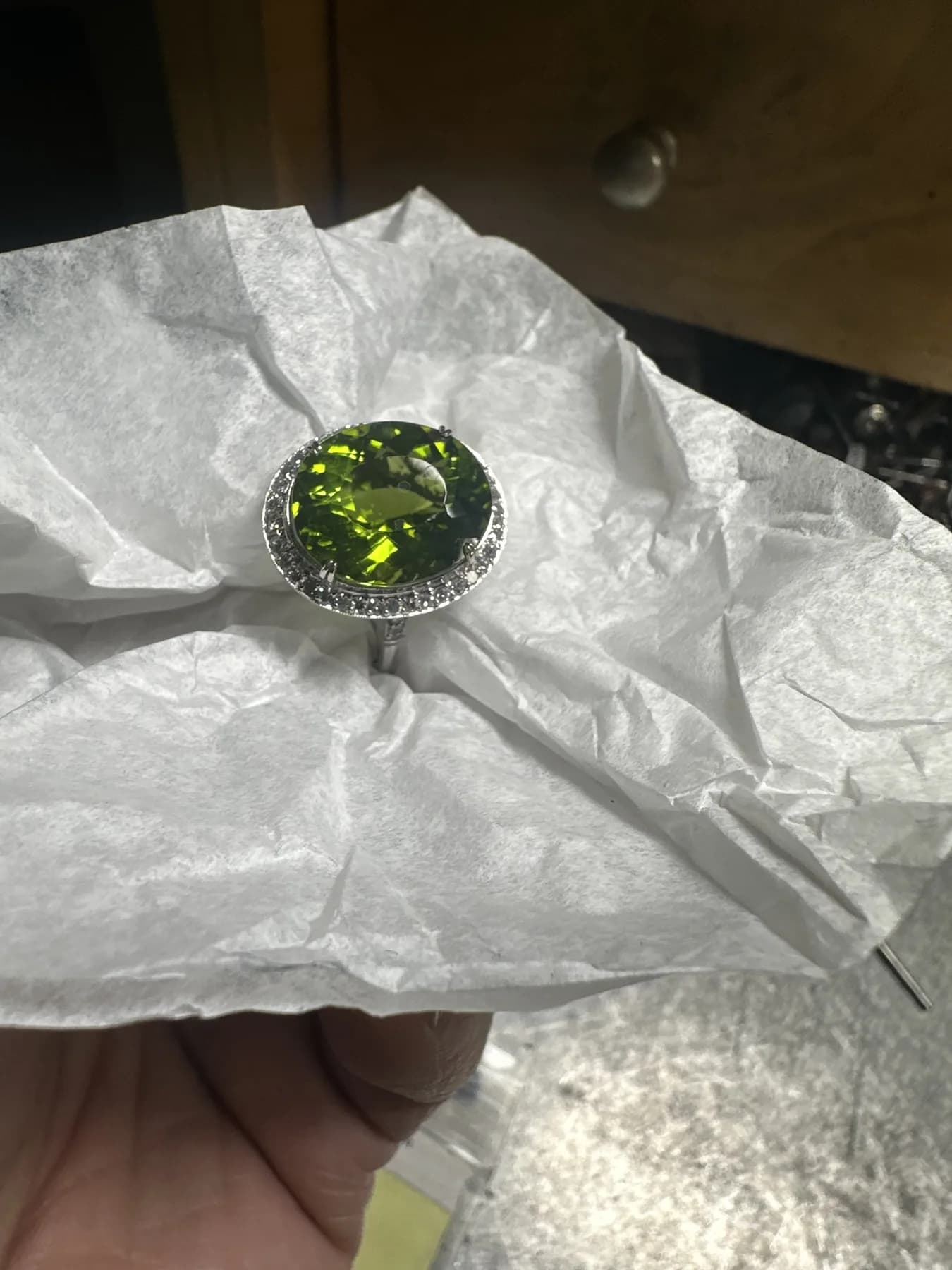 Round green gemstone ring with a halo of small colorless stones at the jeweler's bench